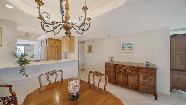 carpeted dining room featuring an inviting chandelier, a tray ceiling, and ornamental molding