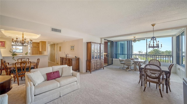 living room featuring an inviting chandelier, a tray ceiling, light carpet, and a textured ceiling