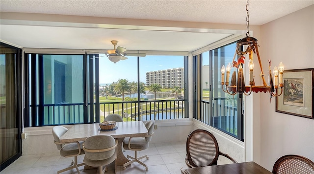 tiled dining space with ceiling fan, a water view, and a textured ceiling