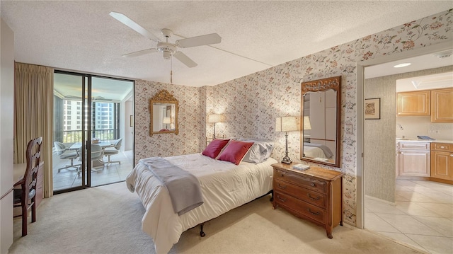 carpeted bedroom featuring ceiling fan, access to outside, a textured ceiling, and ensuite bath