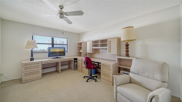 home office featuring ceiling fan, light carpet, and a textured ceiling