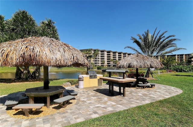 surrounding community with a patio, a water view, area for grilling, and a yard