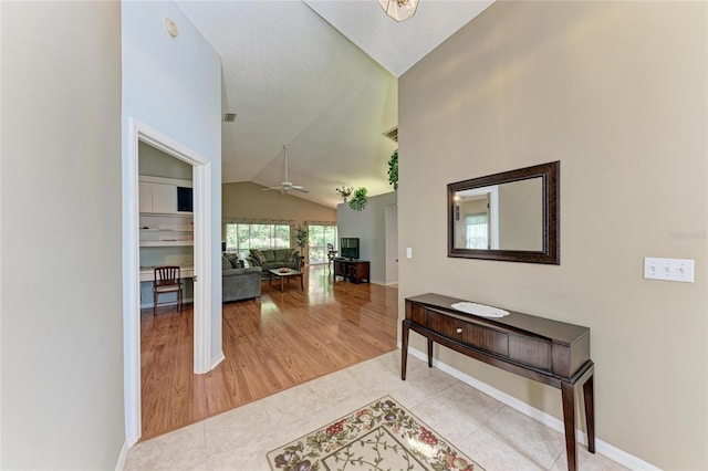 hall featuring light tile patterned floors and vaulted ceiling