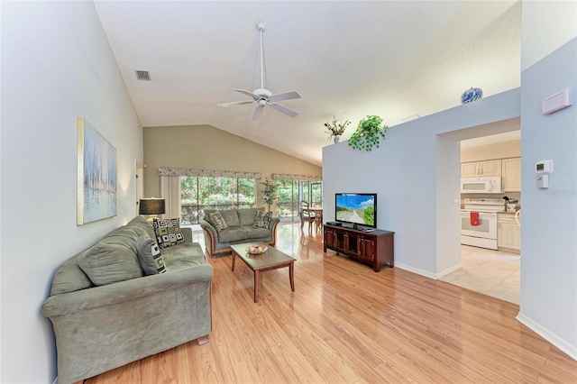 living room with vaulted ceiling, ceiling fan, light hardwood / wood-style floors, and a textured ceiling