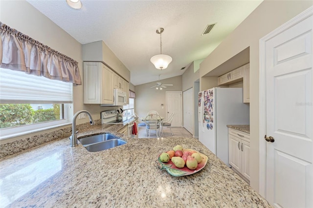 kitchen with lofted ceiling, sink, white appliances, light stone countertops, and decorative light fixtures