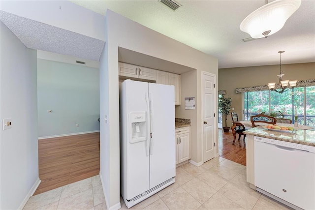 kitchen featuring hanging light fixtures, white appliances, light tile patterned floors, and white cabinets