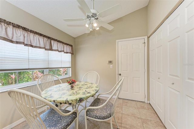 dining space with ceiling fan, vaulted ceiling, a textured ceiling, and light tile patterned floors