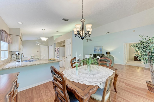 dining area featuring sink, ceiling fan with notable chandelier, a textured ceiling, and light hardwood / wood-style flooring