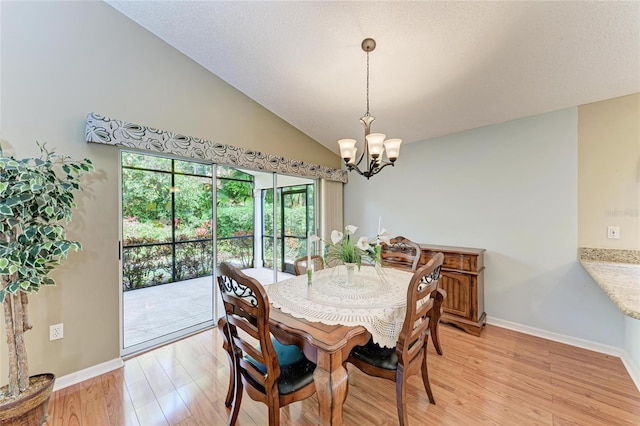 dining room with vaulted ceiling, a chandelier, a textured ceiling, and light hardwood / wood-style floors