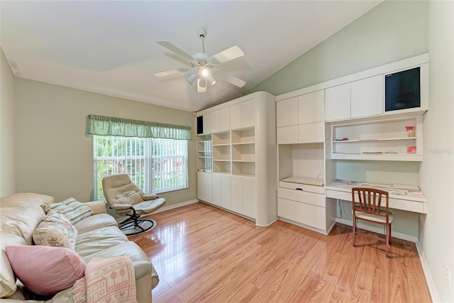 living room with vaulted ceiling, built in desk, ceiling fan, and light wood-type flooring