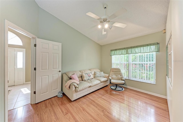 living room with lofted ceiling, a wealth of natural light, ceiling fan, and light wood-type flooring