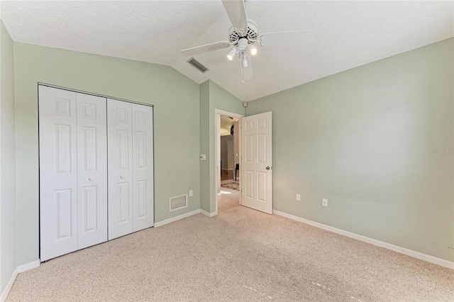 unfurnished bedroom featuring vaulted ceiling, light colored carpet, ceiling fan, a textured ceiling, and a closet