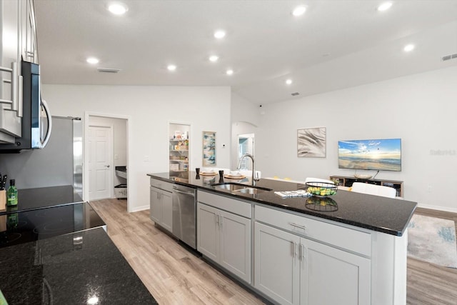 kitchen featuring appliances with stainless steel finishes, sink, a center island with sink, and dark stone counters