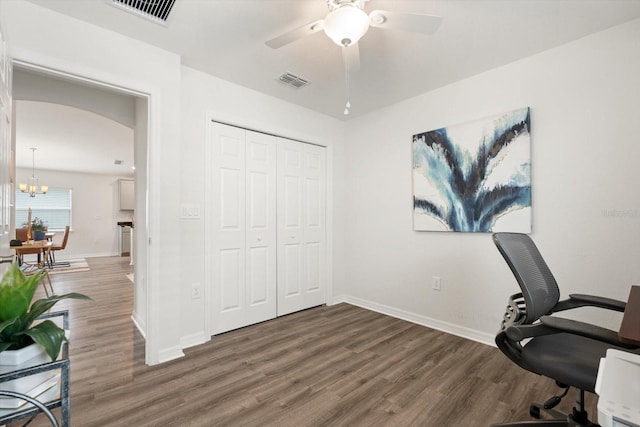 office with dark wood-type flooring and ceiling fan with notable chandelier