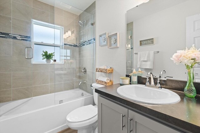 full bathroom with vanity, shower / bath combination with glass door, and toilet