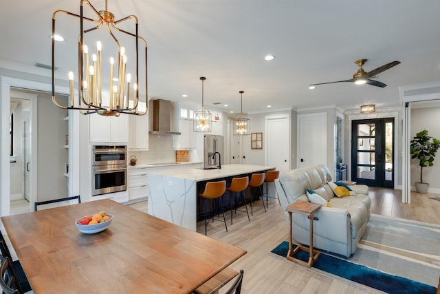 dining area with ceiling fan with notable chandelier, sink, and light hardwood / wood-style floors