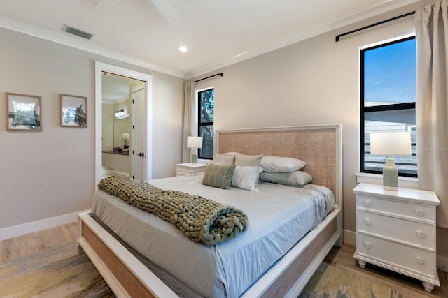 bedroom with ensuite bath, ornamental molding, dark hardwood / wood-style floors, and multiple windows