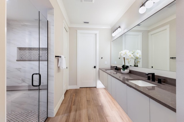 bathroom with crown molding, vanity, an enclosed shower, and hardwood / wood-style flooring