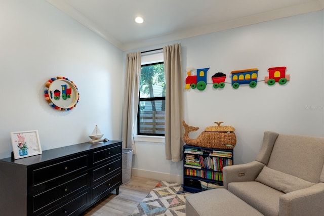 sitting room with crown molding and light hardwood / wood-style floors