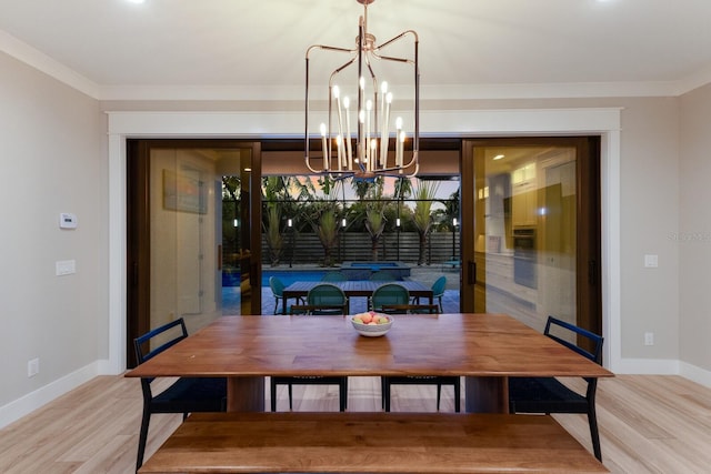 dining room with a notable chandelier, ornamental molding, and light wood-type flooring