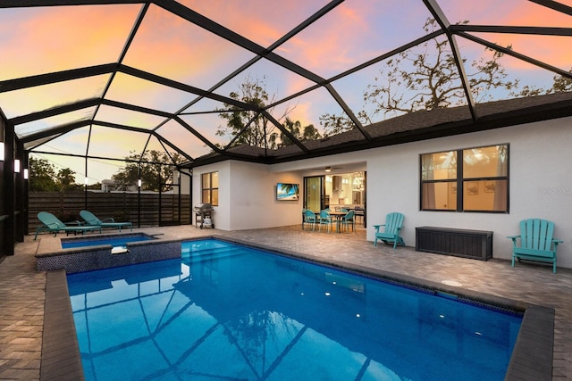 pool at dusk with a lanai, a patio, and ceiling fan