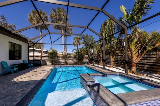 view of pool featuring an in ground hot tub, glass enclosure, and a patio area