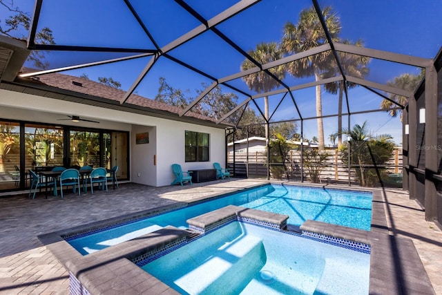 view of swimming pool with an in ground hot tub, ceiling fan, glass enclosure, and a patio area