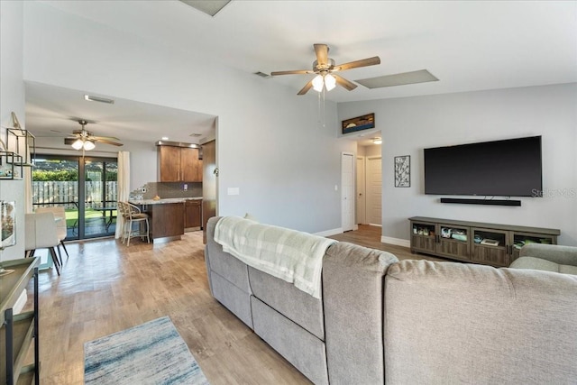 living room with ceiling fan, lofted ceiling, and light hardwood / wood-style floors