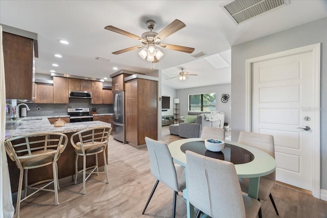 dining room with ceiling fan, sink, and light wood-type flooring