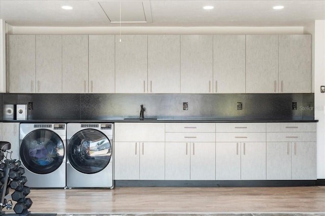 laundry area featuring light hardwood / wood-style floors, sink, cabinets, and washer and dryer