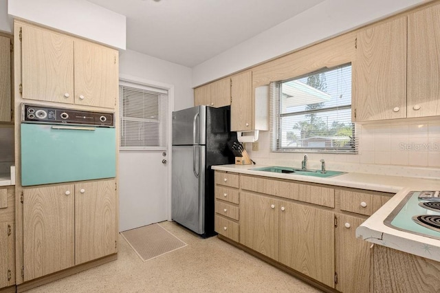 kitchen featuring light brown cabinetry, sink, tasteful backsplash, stainless steel fridge, and wall oven