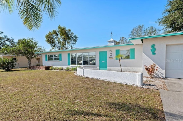 single story home with an attached garage, a front yard, and stucco siding