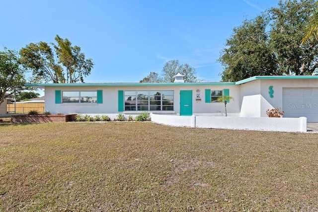ranch-style house with stucco siding, an attached garage, fence, and a front yard