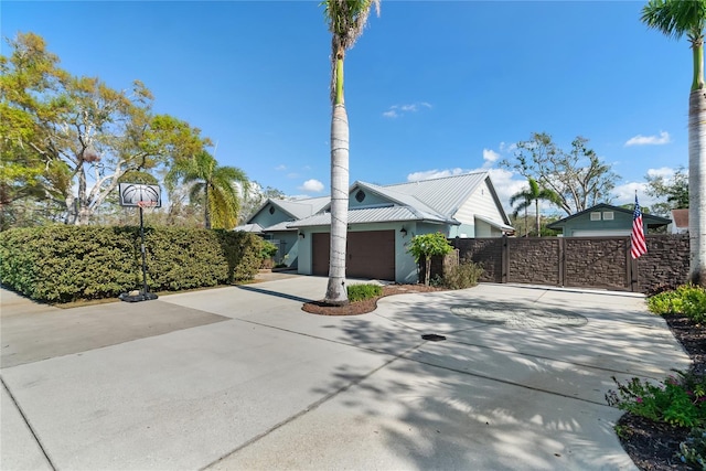 view of front of property featuring fence, metal roof, a garage, driveway, and a gate