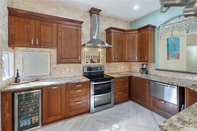 kitchen featuring wine cooler, decorative backsplash, range with two ovens, light stone countertops, and wall chimney exhaust hood