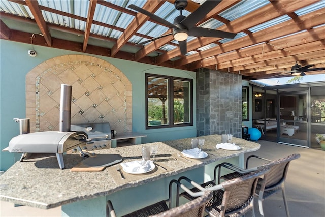 view of patio with a bar, ceiling fan, a grill, and exterior kitchen