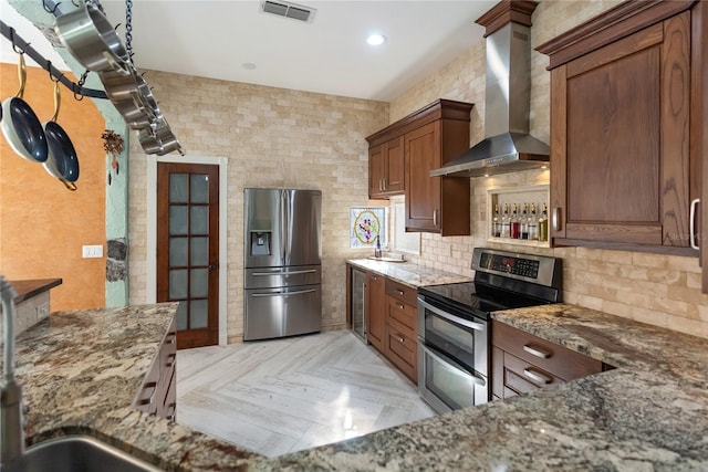 kitchen with stainless steel appliances, dark stone counters, light parquet flooring, beverage cooler, and wall chimney range hood