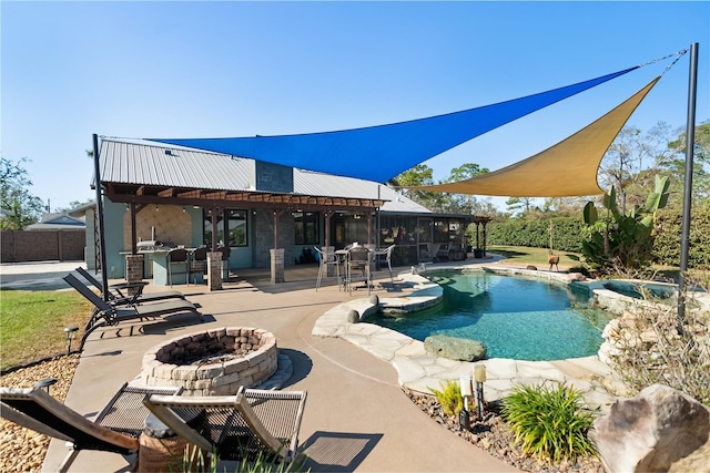 view of swimming pool featuring an outdoor kitchen, a patio area, and a fire pit