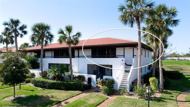 view of front facade with stairs, stucco siding, and a front yard