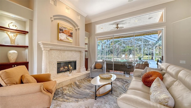 living room featuring crown molding, a fireplace, built in features, and ceiling fan