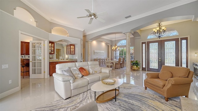 living room with ceiling fan with notable chandelier, decorative columns, a high ceiling, crown molding, and french doors