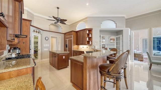 kitchen featuring sink, light stone countertops, kitchen peninsula, and a kitchen island