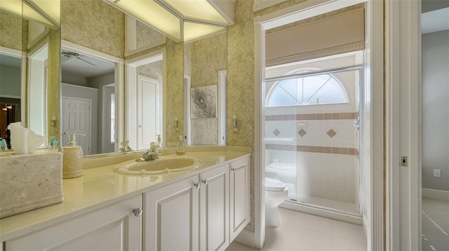 bathroom with ceiling fan, tiled shower, vanity, tile patterned floors, and toilet