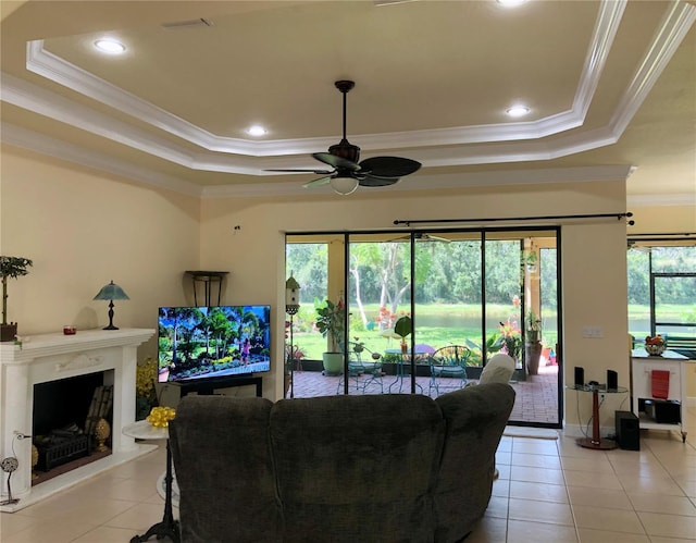 15207 17th Ave E, Bradenton, FL 34212 - living room featuring a tray ceiling, light tile patterned floors, ornamental molding, ceiling fan, and a fireplace