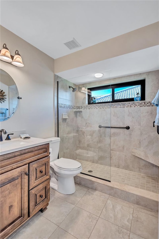 bathroom with vanity, toilet, and a tile shower