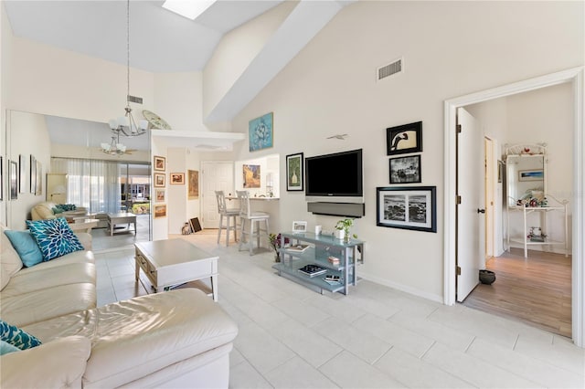 5618 Monte Rosso Rd, Sarasota, FL 34243 - living room featuring an inviting chandelier, light tile patterned floors, a skylight, and high vaulted ceiling