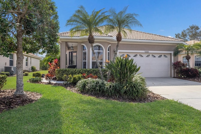 mediterranean / spanish home with cooling unit, a garage, and a front lawn