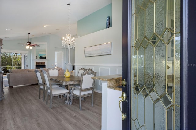 dining space with a tiled fireplace, lofted ceiling, hardwood / wood-style floors, and ceiling fan