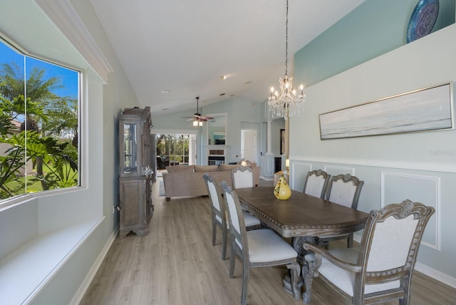 dining space featuring ceiling fan with notable chandelier, vaulted ceiling, and light wood-type flooring