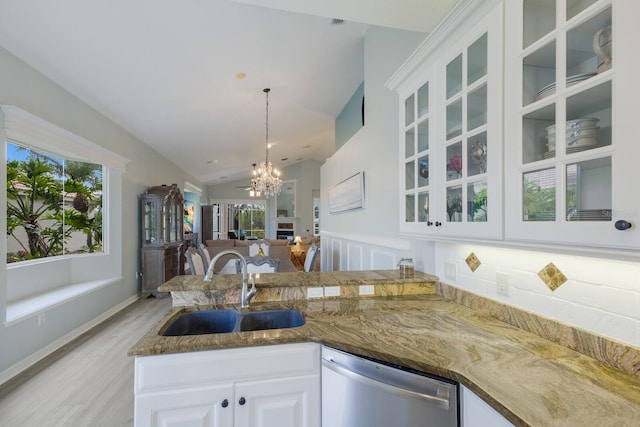 kitchen featuring sink, white cabinets, dark stone counters, hanging light fixtures, and stainless steel dishwasher